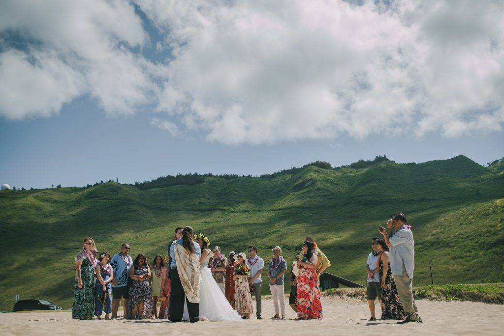Couple stands with their officiant with guests encircled around them.