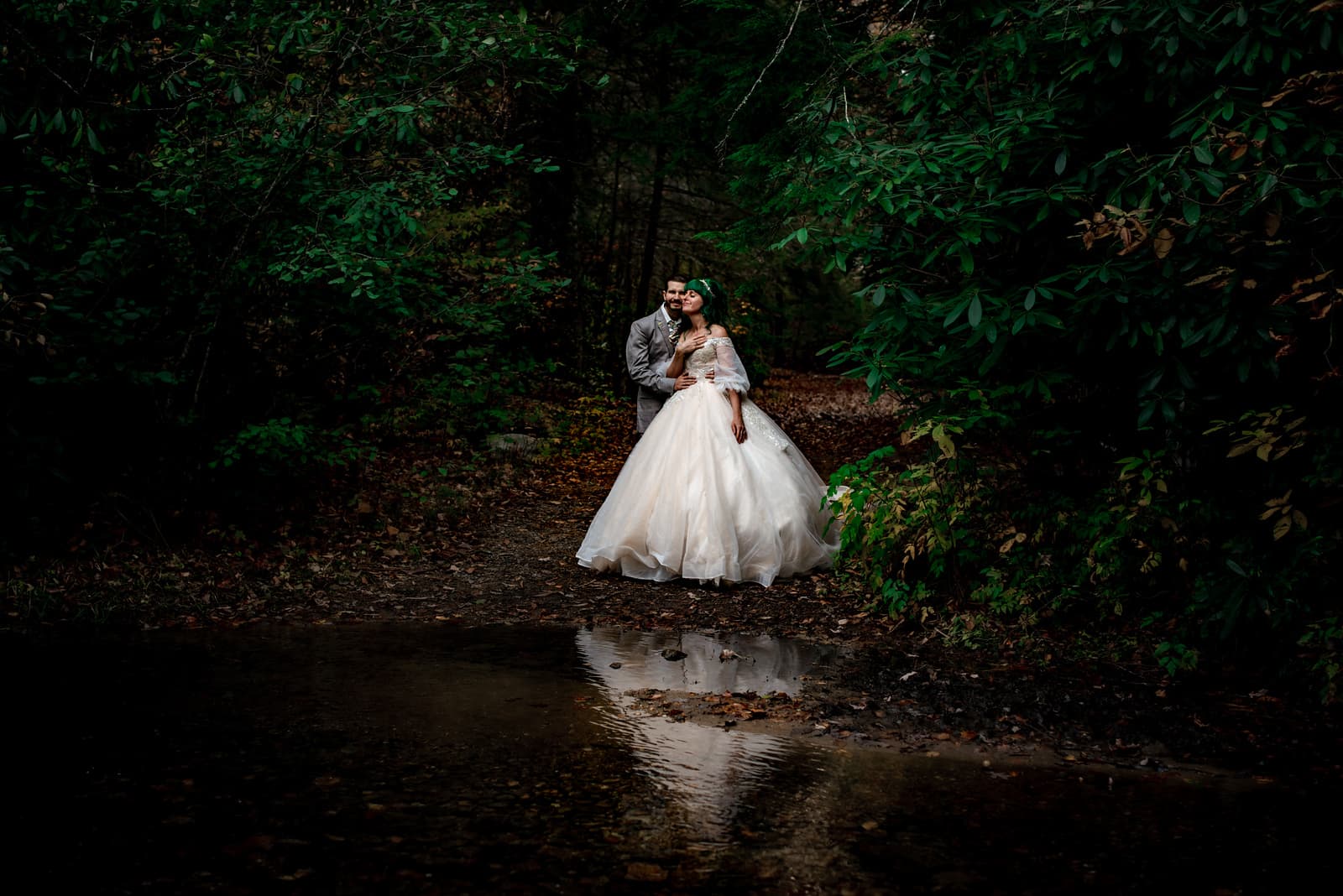 A bride and groom sitting lakeside at Pink Beds in Pigsah National Forest.